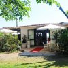Ristorante con ombrelloni, tavolini e giardino con piante e alberi.