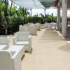 Area esterna con divani bianchi, piante tropicali e ombrellone.