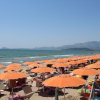 Spiaggia con ombrelloni arancioni e sdraio affollata di bagnanti.
