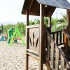 Parco giochi sulla sabbia con struttura in legno e scivolo colorato.