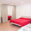 Una camera da letto con un letto matrimoniale rosso, armadio a specchi e comodino.