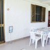 Tavolo e sedie di plastica su terrazza con parete bianca.