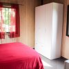 Camera da letto con letto matrimoniale rosso, armadio bianco e tende rosse. Pareti in legno chiaro.
