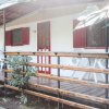 Veranda di legno con balaustra metallica, sedie bianche e persiane rosse.