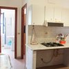 Cucina con piano cottura a gas, pareti con piastrelle bianche e vista di un bagno in fondo.