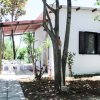 Una piccola casa bianca con veranda e tavolo esterno circondata da alberi.