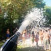 Festa all'aperto con persone coperte di schiuma sparata da un cannone.