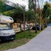 Camper parcheggiato in un'area camping con alberi e vialetto.