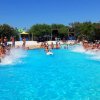 Piscina affollata con persone che si divertono e spruzzi d'acqua.