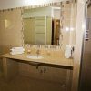 Bagno moderno, con ampio specchio, doccia e lavandino, rivestito in piastrelle beige.