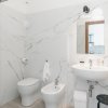 Bagno moderno con sanitari bianchi e pareti in marmo.