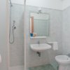 Bagno con doccia, lavabo e bidet in ceramica bianca.