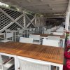 Area pranzo all'aperto con tavoli e sedie bianche.