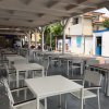 Spazio esterno con tavoli e sedie bianche.