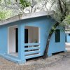 Bungalow blu con veranda aperta e sedia bianca.