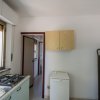 Cucina con fornello, finestra e piccolo frigo bianco.