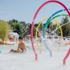 Una piscina con giochi d'acqua e bambini che giocano.
