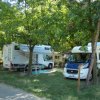 Due camper parcheggiati in un'area ombreggiata con alberi e prato.