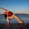 Donna fa yoga al tramonto su un molo.