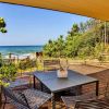 Terrazza con tavolo e sedie vista mare, circondata da vegetazione.