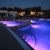 Piscina illuminata di viola di notte, con gradini sott'acqua.