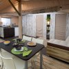 Interno di una tenda con tavolo apparecchiato e cucina.