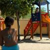 Parco giochi con scivolo arancione e bimbi che giocano.