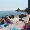 Persone su una piattaforma rocciosa vicino al mare.