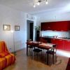 Soggiorno con divano a righe arancioni e cucina rossa.