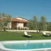 Vista di una casa con piscina e sedie a sdraio immerse nel verde.