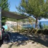 Camper parcheggiato vicino al mare con una bicicletta sul retro e una tenda ombreggiante.