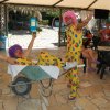Due clown in abiti colorati, uno su una carriola e l'altro che lo spinge, entrambi sorridenti.