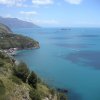 Vista panoramica di una costa con mare azzurro e colline verdi.