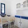 Sala da pranzo con tavolo apparecchiato, credenza bianca e blu, pavimento decorato e finestra.