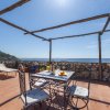 Terrazza con tavolo e sedie, vista mare, sotto pergola di legno.