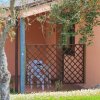 Casa rosa con grata in legno e sedie bianche.