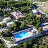 Vista aerea di un complesso turistico con piscina e edifici circondati da alberi.