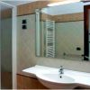 Bagno moderno con doccia, specchio e asciugacapelli a muro.