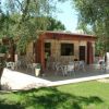 Un bar in pietra con terrazza all'aperto, circondato da prato verde e alberi.