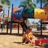 Bambini giocano in un parco giochi colorato con scivoli e tunnel.