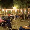 Persone sedute all'aperto in un caffè illuminato di notte.
