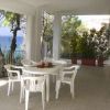 Tavolo e sedie bianche su una veranda con vista sul mare.