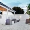 Patio moderno con sedie, accanto a un albero e una pergola bianca.