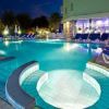 Piscina di notte con gradini curvi, sedie a sdraio e ombrelloni.