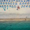 Vista dall'alto di una spiaggia con ombrelloni blu.