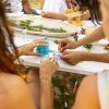 Persone intrecciano fili blu a un tavolo.