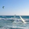 Persone che praticano windsurf e kitesurf su onde blu.