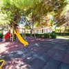 Parco giochi con scivolo e area ombreggiata.