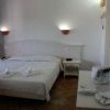Una camera da letto con letto matrimoniale, luci a muro accese, bottiglia e bicchieri su un tavolo.