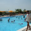 Piscina affollata, bagnino cammina sul bordo.